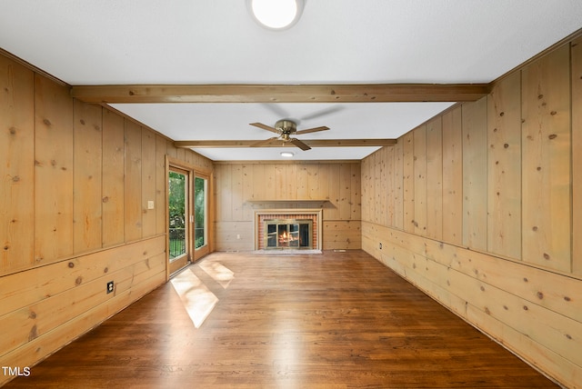 unfurnished living room with beamed ceiling, wood walls, and hardwood / wood-style flooring