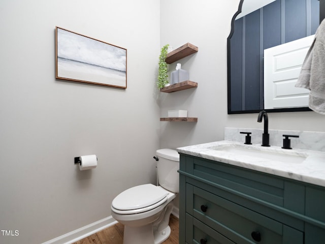 bathroom with toilet, baseboards, wood finished floors, and vanity