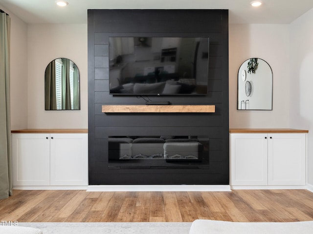 living area with a large fireplace, light wood finished floors, and recessed lighting