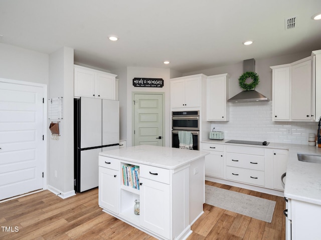 kitchen featuring open shelves, white cabinetry, freestanding refrigerator, a center island, and wall chimney exhaust hood