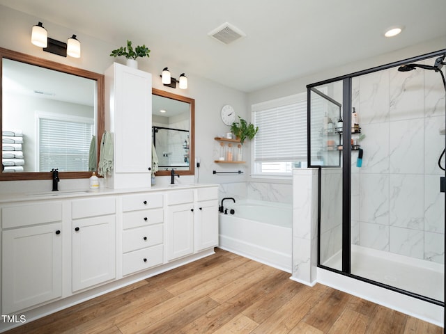 bathroom featuring a stall shower, visible vents, a sink, and wood finished floors