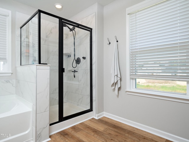 bathroom with baseboards, wood finished floors, and a shower stall