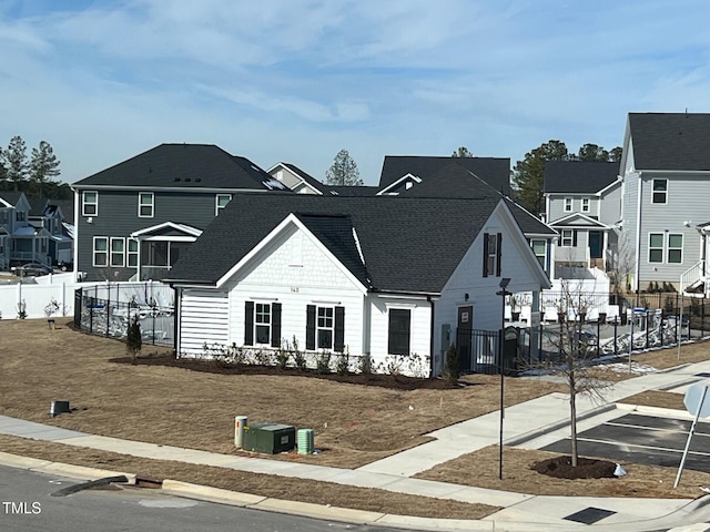 view of front of home featuring a shingled roof, a residential view, and fence