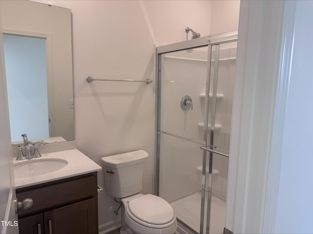 bathroom featuring vanity, toilet, and a shower with door