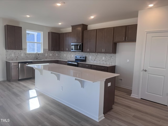 kitchen with a kitchen island, light hardwood / wood-style floors, and appliances with stainless steel finishes