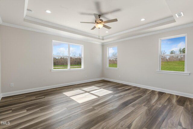 empty room featuring a raised ceiling, ornamental molding, dark hardwood / wood-style flooring, and ceiling fan