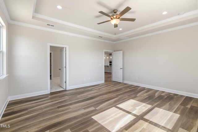 unfurnished bedroom featuring a tray ceiling, ceiling fan, and dark hardwood / wood-style flooring