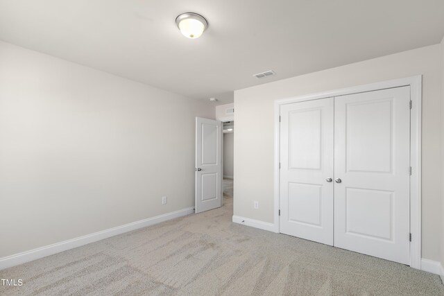 unfurnished bedroom featuring light colored carpet and a closet