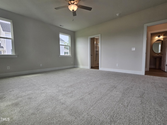 unfurnished bedroom featuring carpet, a ceiling fan, a sink, baseboards, and ensuite bathroom