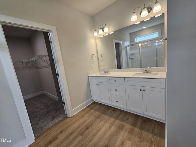 full bath with wood finished floors, a sink, a walk in closet, and a stall shower