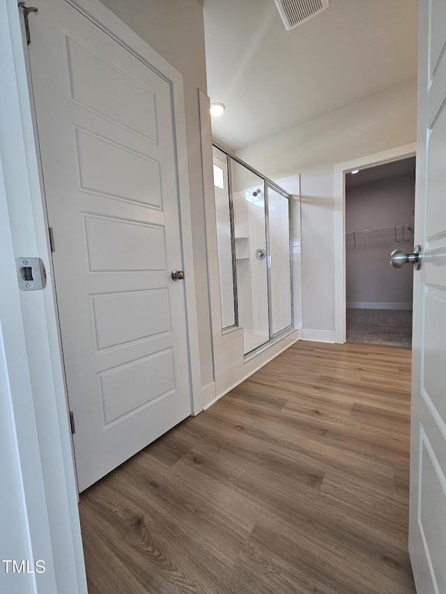 hallway with baseboards, wood finished floors, and visible vents