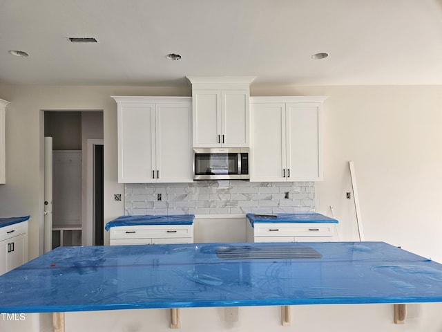 kitchen with tasteful backsplash, white cabinetry, a breakfast bar area, and a kitchen island