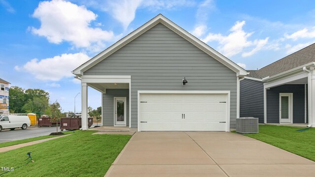 view of front of home featuring an attached garage, driveway, central AC, and a front lawn