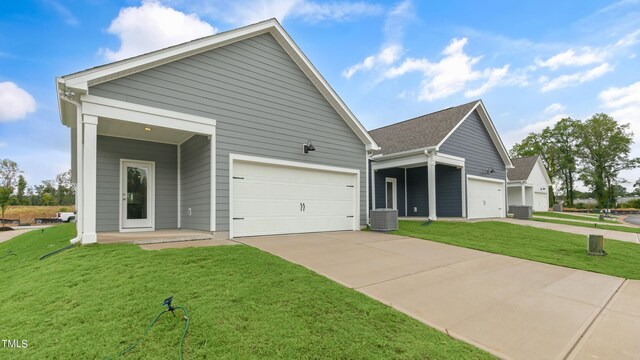 view of front of home featuring cooling unit, an attached garage, a front lawn, and concrete driveway