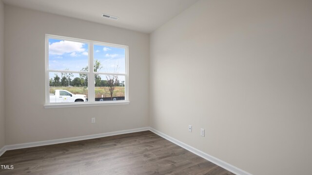empty room with baseboards, wood finished floors, visible vents, and plenty of natural light