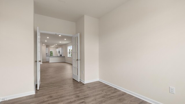 hall with baseboards, wood finished floors, and recessed lighting