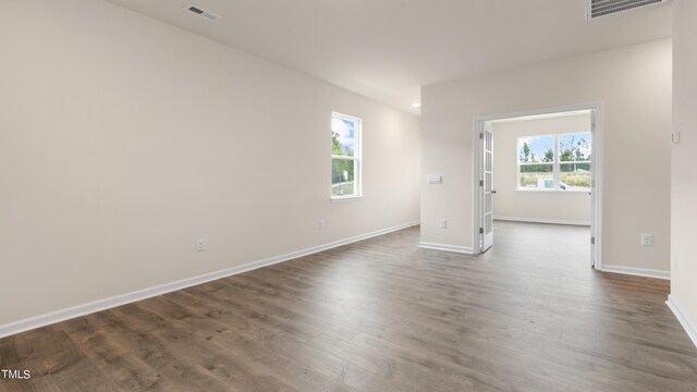 unfurnished room featuring baseboards, visible vents, and dark wood-style floors