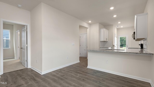 kitchen featuring white cabinets, recessed lighting, dark wood-style floors, a sink, and light stone countertops