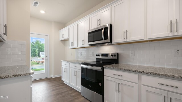 kitchen featuring dark wood finished floors, light stone counters, stainless steel appliances, visible vents, and white cabinetry