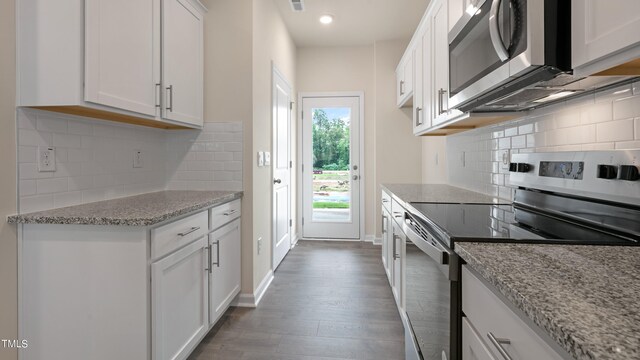 kitchen featuring white cabinets, stainless steel appliances, dark wood-style floors, tasteful backsplash, and light stone counters