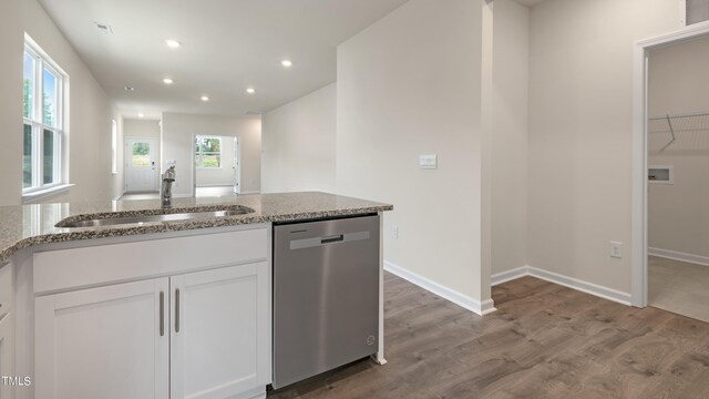 kitchen with wood finished floors, a sink, dishwasher, light stone countertops, and recessed lighting