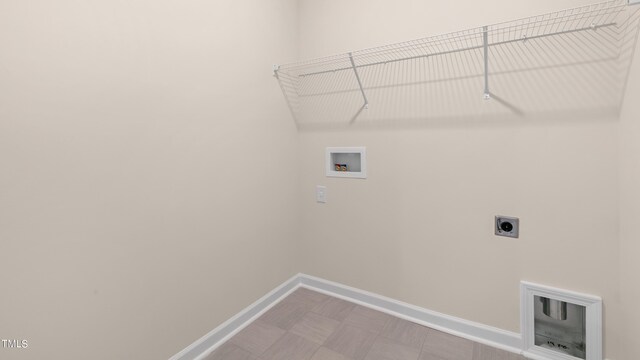 clothes washing area with tile patterned floors, hookup for a washing machine, electric dryer hookup, baseboards, and laundry area