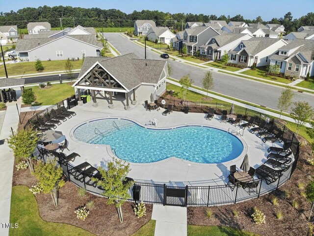 community pool featuring fence, a residential view, and a patio