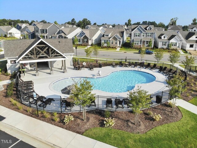 community pool featuring a residential view, a patio, and fence
