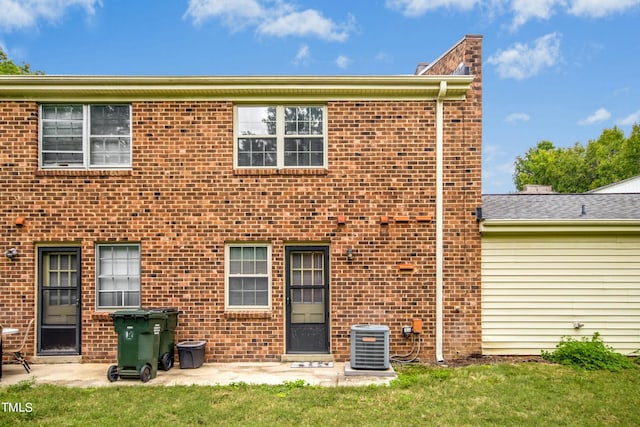 rear view of property with central air condition unit and a yard