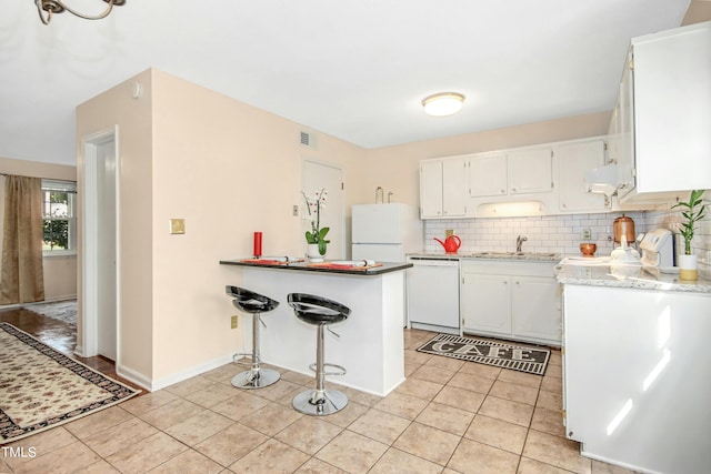 kitchen featuring kitchen peninsula, sink, white appliances, and white cabinetry