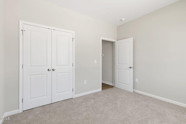 unfurnished bedroom with light carpet and a closet