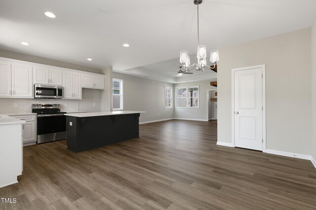 kitchen with appliances with stainless steel finishes, white cabinetry, ceiling fan with notable chandelier, decorative light fixtures, and dark hardwood / wood-style floors