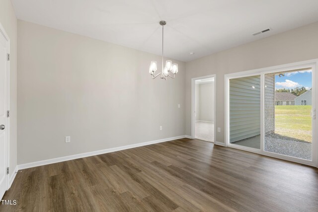 empty room with an inviting chandelier and dark hardwood / wood-style flooring