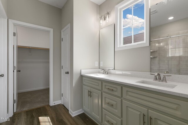 bathroom featuring wood-type flooring, vanity, and tiled shower