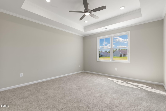 empty room with carpet floors, crown molding, a tray ceiling, and ceiling fan