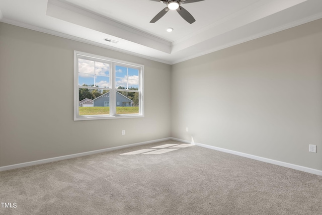 carpeted spare room with a tray ceiling, ceiling fan, and crown molding