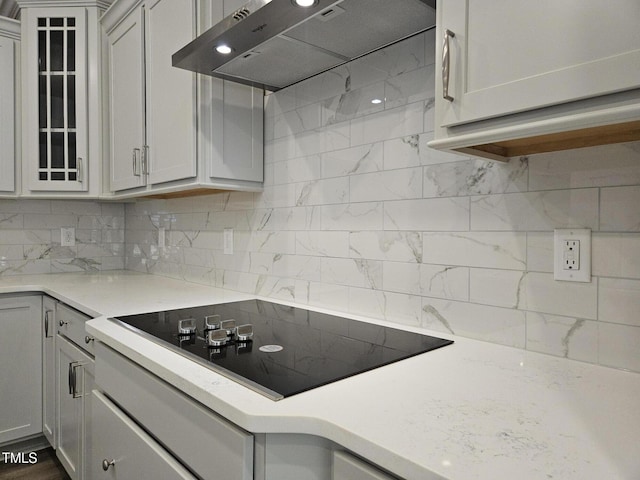 145 Green Haven Blvd Lot # 83, Youngsville, NC 27596 - kitchen with black electric stovetop, exhaust hood, decorative backsplash, glass insert cabinets, and light stone countertops