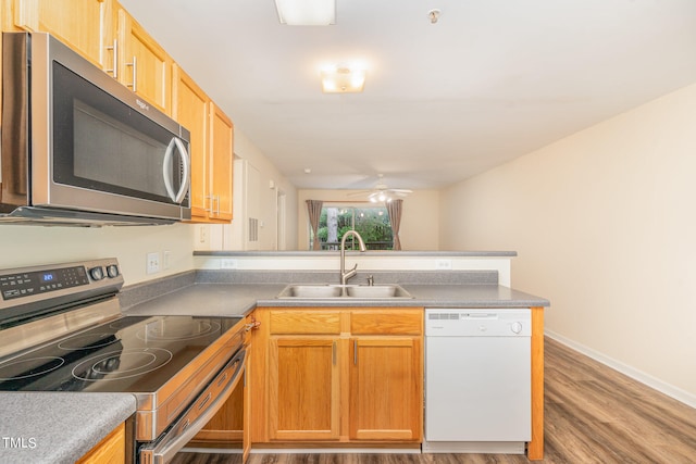 kitchen featuring ceiling fan, sink, kitchen peninsula, wood-type flooring, and stainless steel appliances