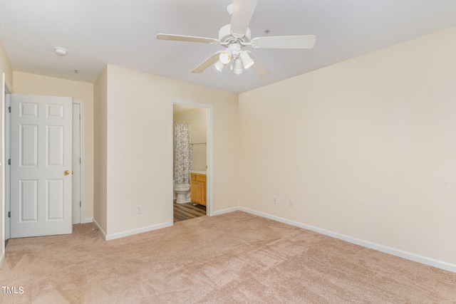 unfurnished bedroom featuring ceiling fan, ensuite bath, and light carpet