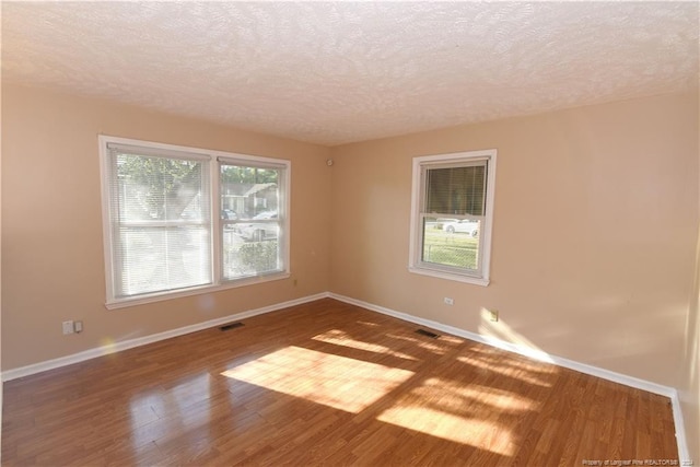 spare room with a textured ceiling and hardwood / wood-style floors