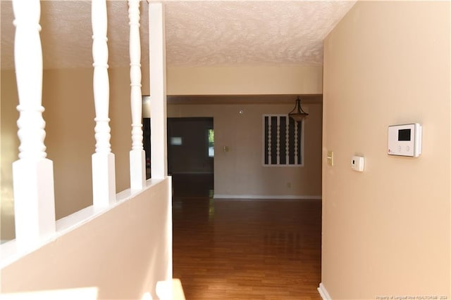 corridor with a textured ceiling and dark hardwood / wood-style flooring