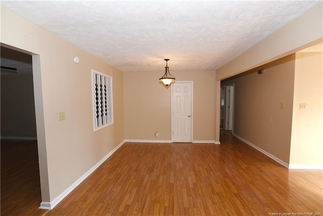 unfurnished room featuring wood-type flooring and a textured ceiling