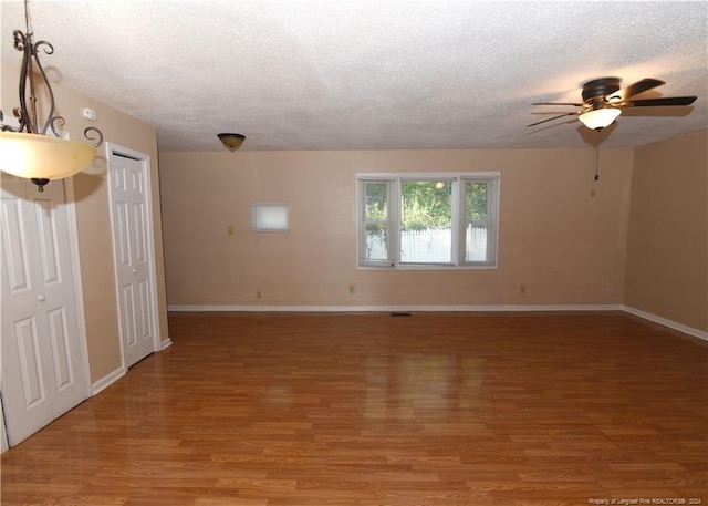 unfurnished room featuring ceiling fan, hardwood / wood-style floors, and a textured ceiling