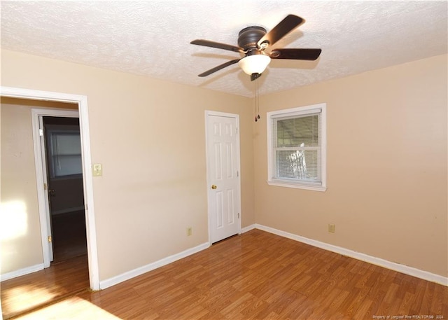 unfurnished bedroom featuring a textured ceiling, hardwood / wood-style floors, ceiling fan, and a closet