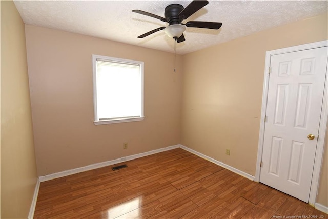 empty room with wood-type flooring, ceiling fan, and a textured ceiling