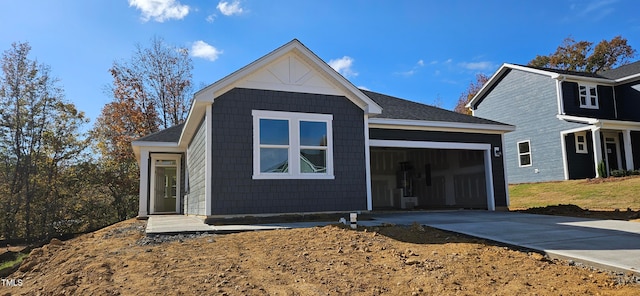 view of front facade featuring a garage, concrete driveway, and roof with shingles