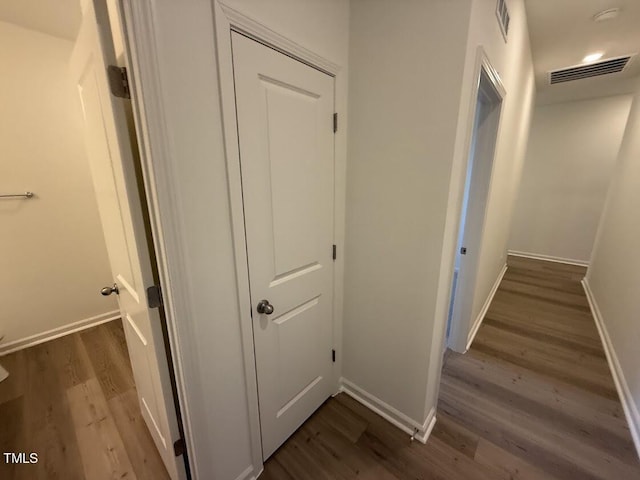 hallway featuring baseboards, visible vents, and dark wood finished floors