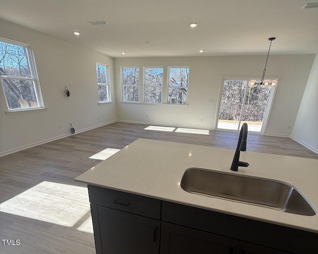 kitchen featuring open floor plan, light countertops, a sink, and pendant lighting