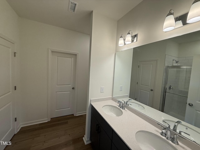 full bathroom featuring visible vents, a sink, a shower stall, and wood finished floors