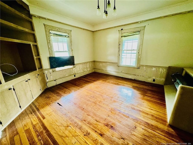 unfurnished bedroom featuring multiple windows, wood-type flooring, and crown molding